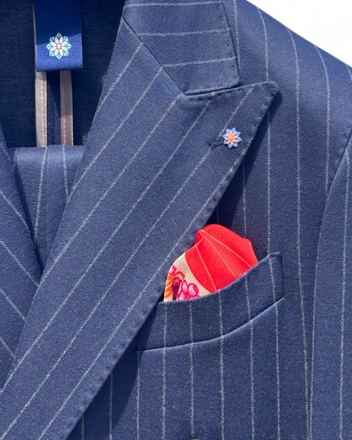 Dettaglio del rever dell'abito doppiopetto uomo elegante Aomori con pochette rossa e spilla floreale, perfetto per eventi e lavoro.