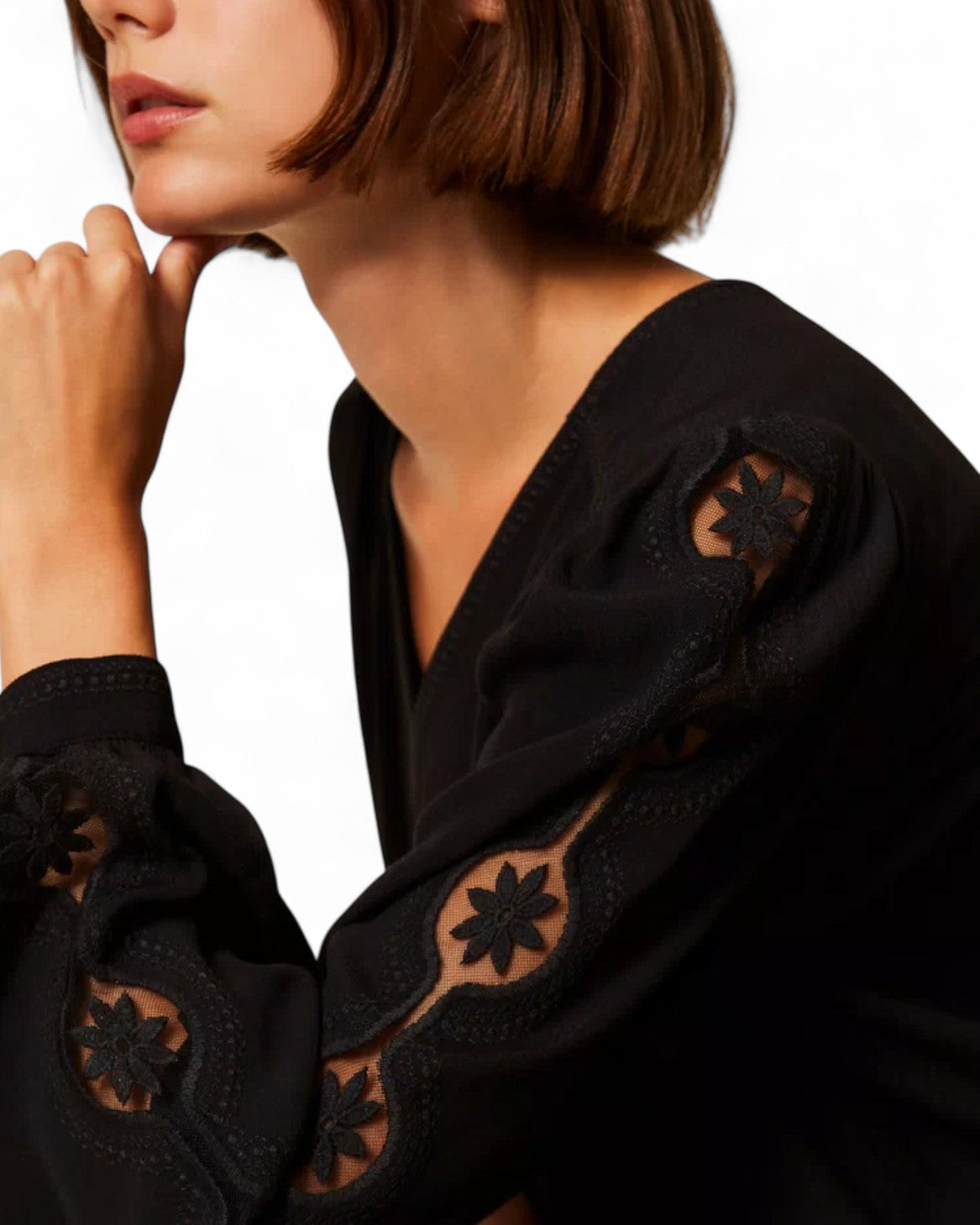 Dettaglio manica blusa in crêpe nero con ricami floreali traforati, ideale per un tocco sofisticato nella maglieria invernale da donna.