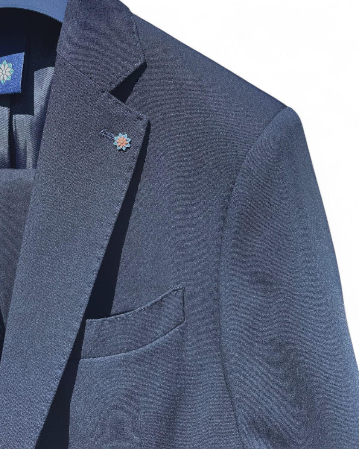 Particolare del rever e taschino dell'Abito Uomo Elegante Kobe, con spilla decorativa e tessuto raffinato per uno stile impeccabile.