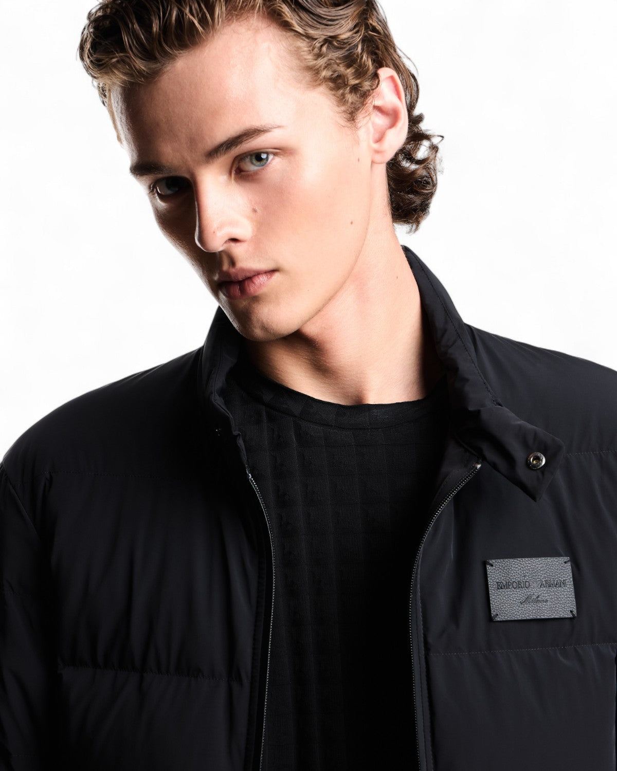 Dettaglio del colletto e logo sul petto del piumino trapuntato uomo in spandex, perfetto per outfit invernali eleganti e funzionali.