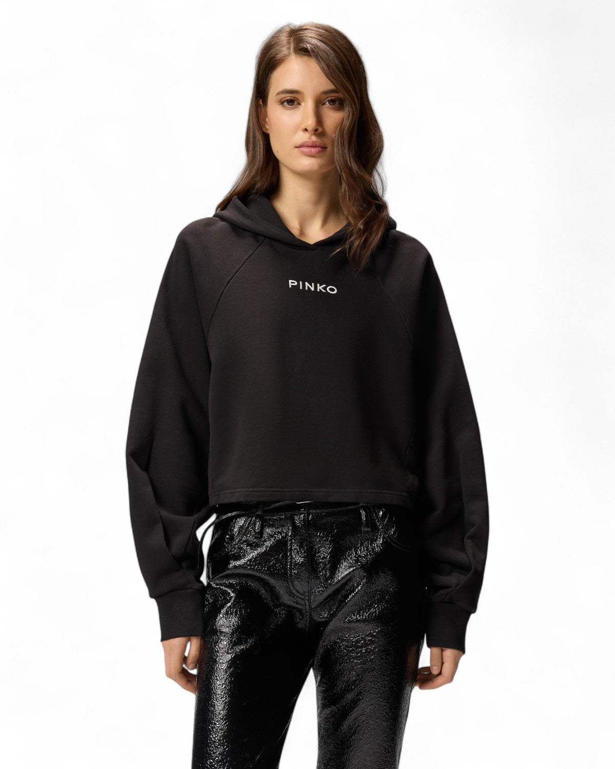 Modella indossa Felpa Cropped con Cappuccio e Ricamo Logo PINKO nera. Look casual elegante, perfetta per outfit da ufficio o tempo libero.