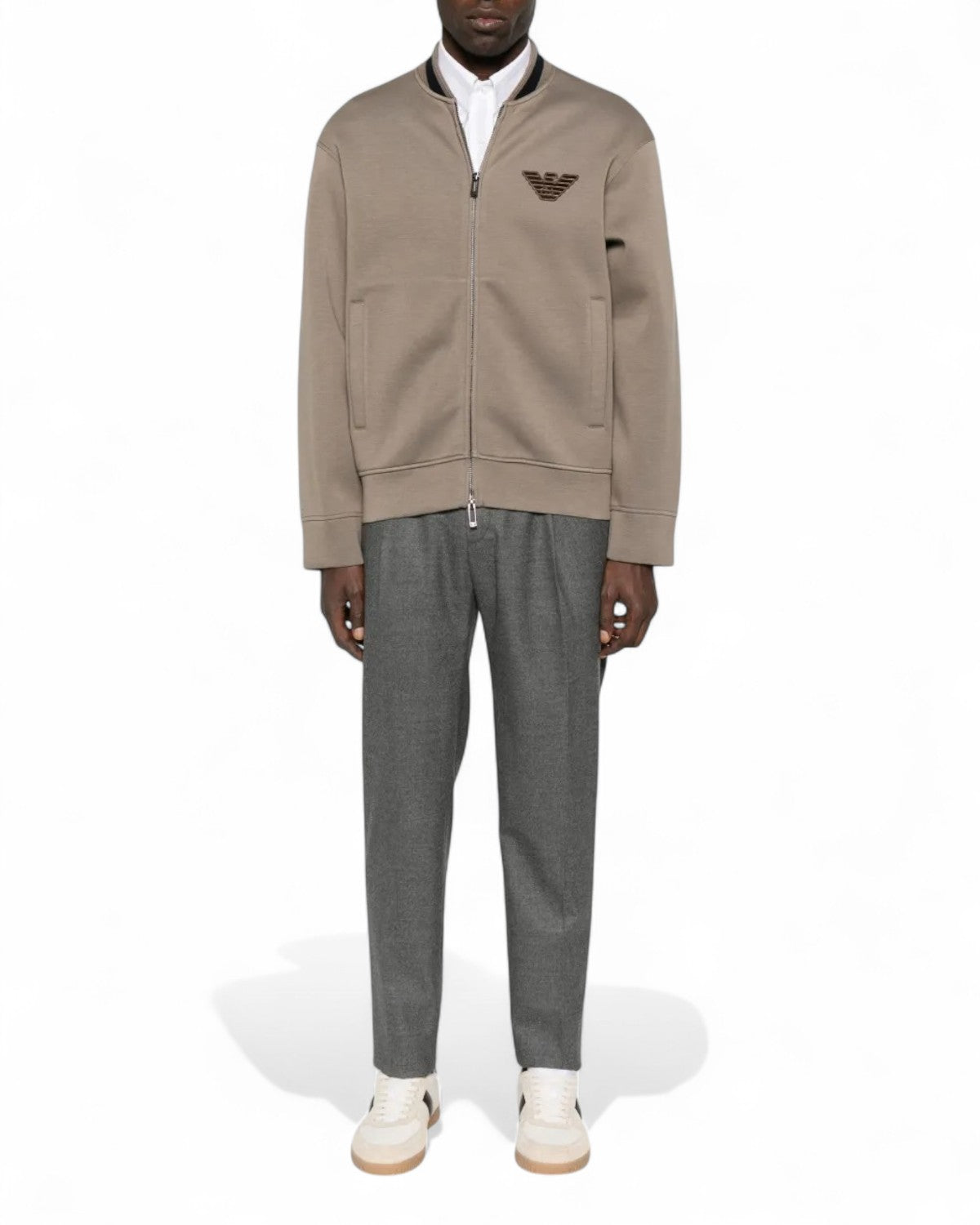 Felpa in double jersey da uomo con collo bomber e patch aquila, abbinata a pantaloni grigi per un look invernale sofisticato.