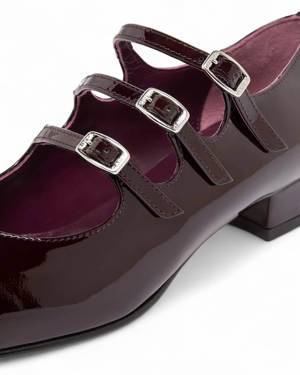 Primo piano delle Carel Ariana Mary Janes in vernice marrone, evidenziando le fibbie argentate e la finitura lucida.