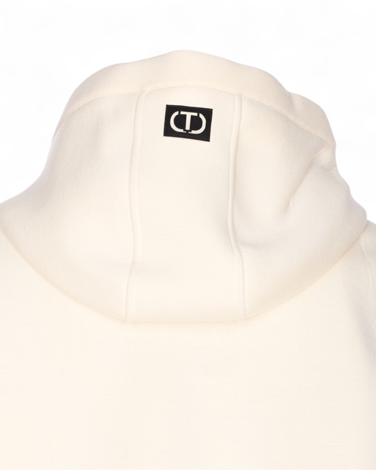 Particolare del cappuccio con logo Twinset sul retro della giacca panna. Capo outerwear raffinato per donna FW26.