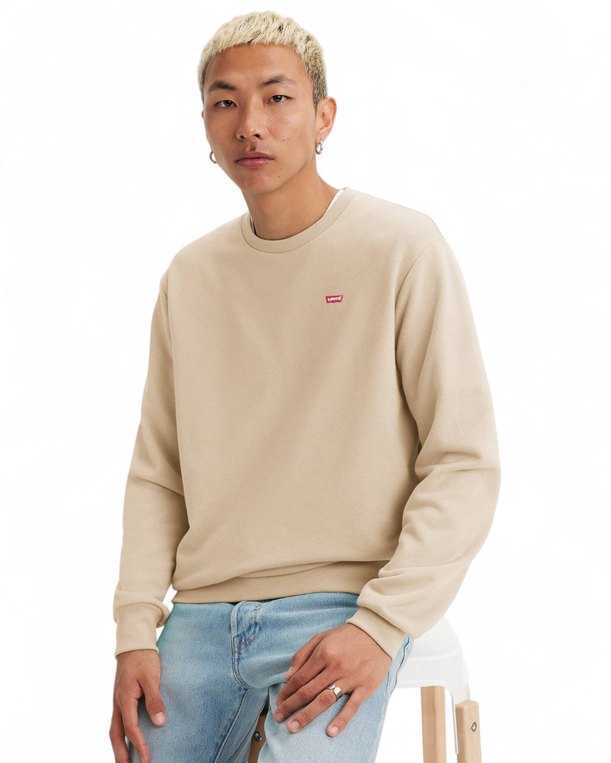 Felpa Girocollo Cotone Levi's beige indossata da modello seduto, perfetta per un look casual e versatile da uomo.